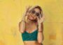 woman in blue bralette holding sunglasses putting on her eyes