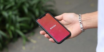 a person holding a red cell phone in their hand