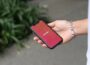 a person holding a red cell phone in their hand