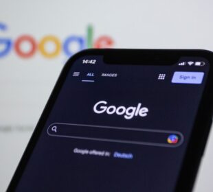 a close up of a cell phone with the google logo in the background