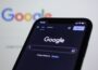 a close up of a cell phone with the google logo in the background