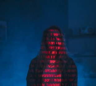 A mysterious silhouette with red binary code projected over the face, set against a dark, moody background.