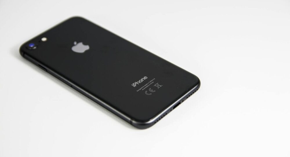 Black smartphone placed on a clean white surface, highlighting modern design and tech elegance.