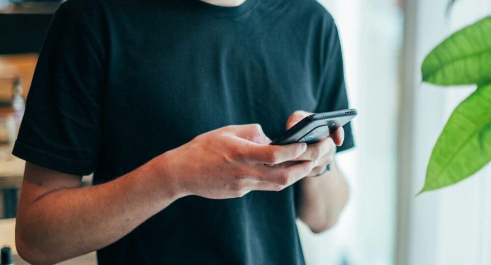 man in black crew-neck top using smartphone