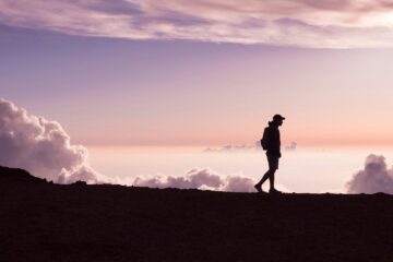silhouette of person walking under white clouds