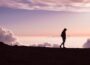silhouette of person walking under white clouds