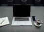 turned-off MacBook Pro between cup of coffee, iPhone, notebook, and pen