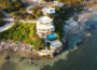 A stunning aerial view of a luxury villa on Grand Cayman with a seafront pool and lush greenery.