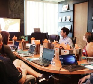 man standing in front of people sitting beside table with laptop computers