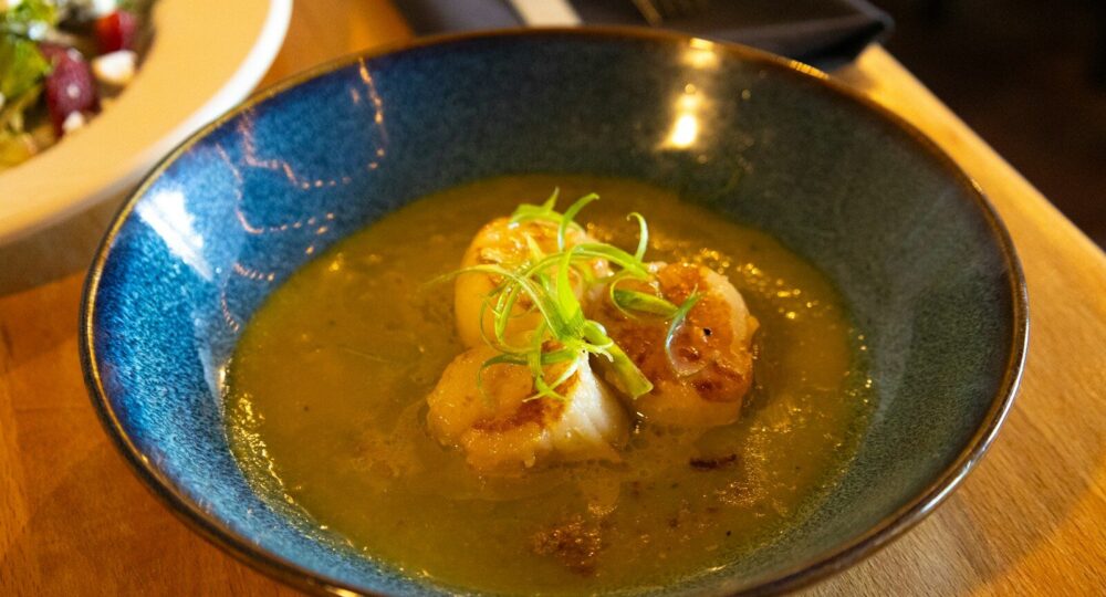 Scallops in a greenish broth with garnish