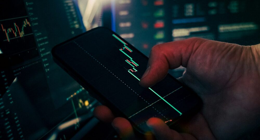 Trader analyzing stock market data on smartphone and phone