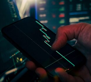 Trader analyzing stock market data on smartphone and phone